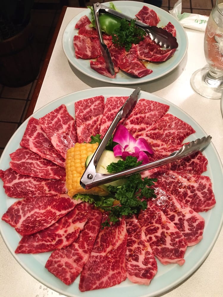 Yakiniku spread with multiple plates of beef and sides on the table