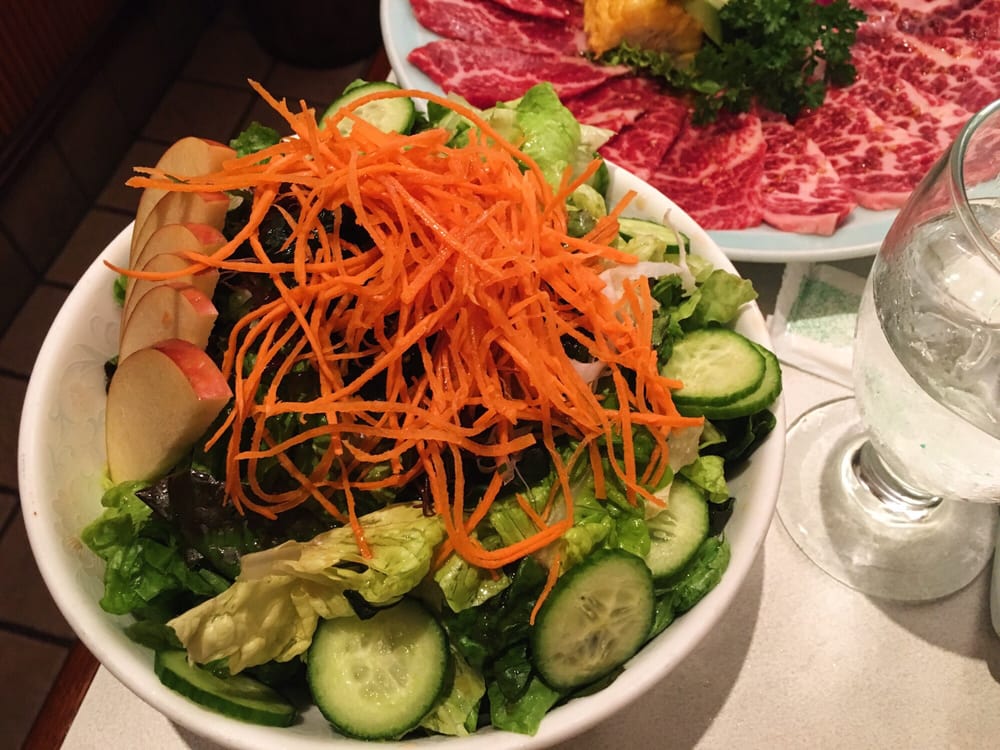 Cold noodle dish served in a bowl alongside grilled meats